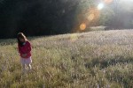 Girl in Wild Grass Meadow. Lens Flare.
