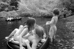 Boy holds rope of innertube with kids. Infrared photography of the Big Sur River on the summer solstice.