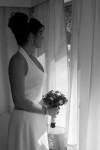 Black and white photo of bride waiting at window