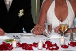 Bride and groom hold hands at sweetheart table with rose petals wedding reception Los Gatos Hotel and Spa