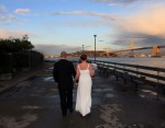 bride and groom walk down pier 1 in san francisco golden hour evening light clouds and bay bridge